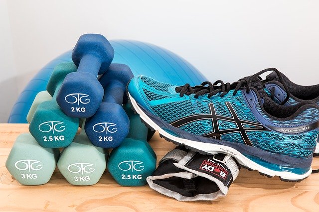 A pair of blue dumbbells next to a shoe.