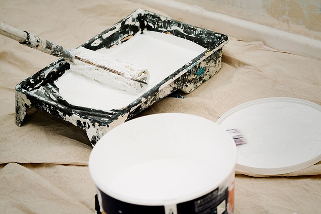 A paint can and a painting tray on the floor.